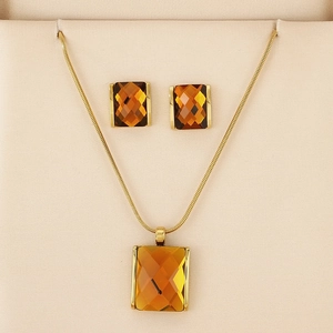 Detail of luxury gold snake chain necklace and amber square glass earrings in a gift box