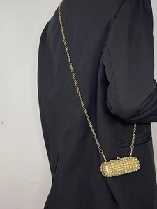Detailed view of luxury gold rhinestone cylinder crossbody bag with chain strap