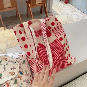 Detailed close-up of cotton tote bag showing red polka dots and interior brand label
