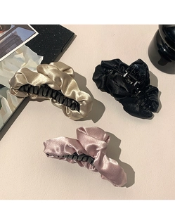 Dettaglio dei mollettoni per capelli in raso plissettato color oro, nero e rosa cipria