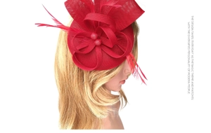 Detail of red fascinator hat featuring delicate feathers and mesh net for party