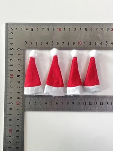 Detailed view of four mini red felt Christmas hats with rulers showing small size measurements
