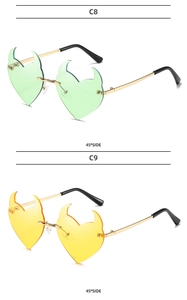 Detail of rimless heart-shaped devil sunglasses with green and yellow lenses and gold metal stems