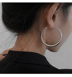 Gros plan de boucles d'oreilles créoles argentées portées par un mannequin au style moderne