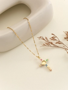 Detailed close-up of a golden cross necklace with colorful zircon stones on a clean background
