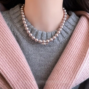 Detailed view of pink pearl necklace on model's neck with soft metallic luster