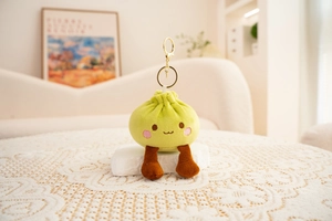 Detail of cute green plush bun pendant with embroidery face and gold keychain