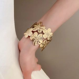 Detailed macro view of large golden 3D flower cuff bracelet with brushed metal texture