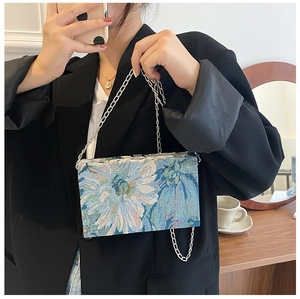 Close-up of floral jacquard embroidery fabric and silver chain on small square box bag