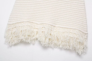 Détail du tissu en tricot blanc avec des franges denses et une texture tissée fine