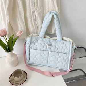 Close-up of light blue quilted puffer bag with a pink strap and cloud-like texture