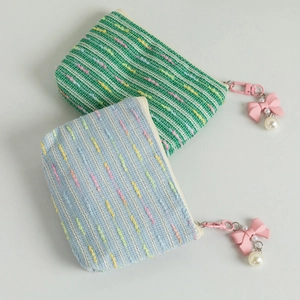 Detail of knitted coin purses with pink metal zippers, bow charms, and pearl beads
