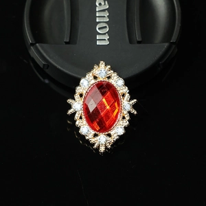 Close-up of vintage oval red gemstone pendant with gold floral frame and white rhinestones