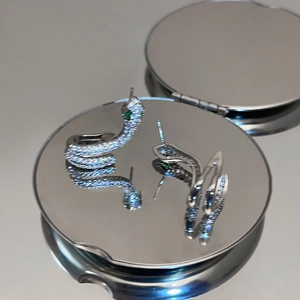 Détails macro des boucles d'oreilles serpent en argent avec zircons et yeux verts