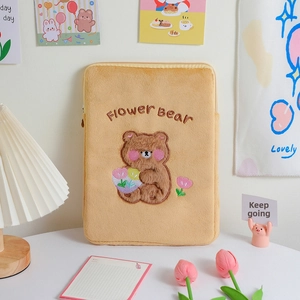 Detailed view of yellow plush tablet sleeve with embroidered bear and flower bear text