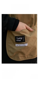 Detail of durable khaki canvas apron featuring large pockets and barista tool labels