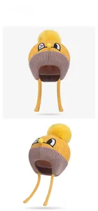 Detail view of yellow knit kids winter hat with pom-pom and cute cartoon embroidery
