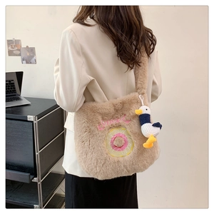 Detail of khaki plush tote bag with sweet embroidery and cute duck charm on a model