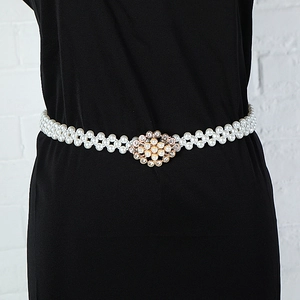 Detail of beaded pearl waist belt with gold floral rhinestone buckle on black dress