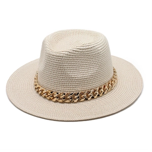 Detailed texture of beige woven straw hat with a bold decorative gold chain accent