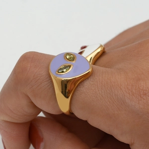 Detailed close-up of 18K gold alien ring with purple enamel and green gem eyes