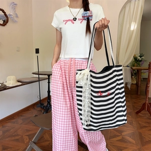 Detail of striped canvas tote with red love embroidery and a large lace bow accent