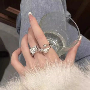 Silver hip-hop ring set with pearl and zircon detail on model's hand with soft lighting
