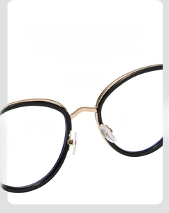 Close-up of adjustable silicone nose pads on black and gold metal cat-eye frames