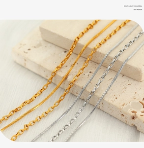 Close-up of mixed gold and silver OT buckle necklaces on a textured stone surface