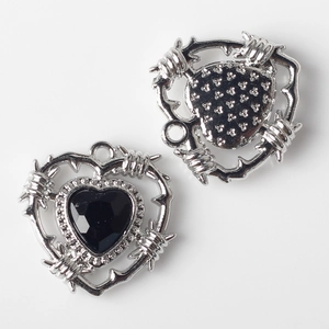 Macro detail of silver heart pendants with black zircon stones and barbed wire punk design