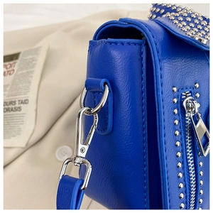 Detail of royal blue leather bag featuring silver studs and high-quality metal zipper