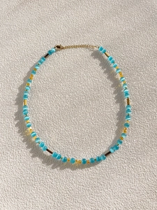 Close-up of glacier blue cat eye beads and heart pendant necklace on white background