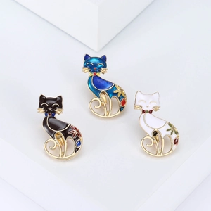 Three elegant cartoon cat brooches in black, blue, and white with floral enamel patterns