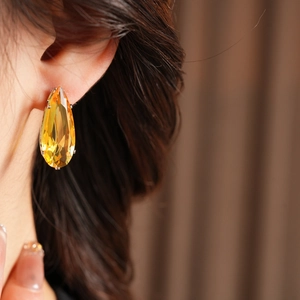 Close-up of elegant gold pear cut zircon earrings worn on the earlobe for style