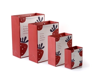 Macro view of red and white paper gift bags with strawberry patterns in four sizes