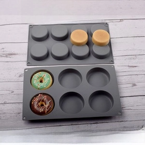 Close-up of gray 6-cavity donut and 8-cavity cylinder silicone baking molds on white wood