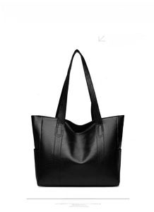 Detail of black faux leather tote bag with natural grain texture and wide shoulder strap