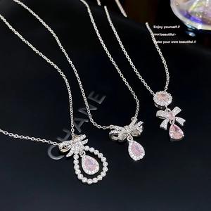 Close-up of bow knot necklaces with pink pear-cut zircon and silver chain detail