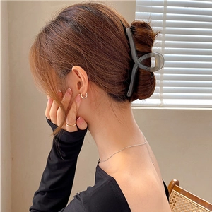 Cross-design grey-black translucent shark hair claw clip worn by a model in soft light