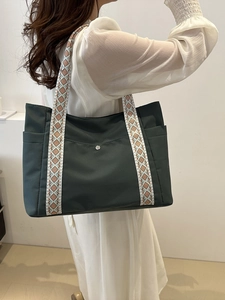 Dettaglio della borsa tote verde scuro con tracolle decorate con motivi geometrici