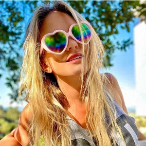 Close-up of pink heart-shaped sunglasses with rainbow iridescent mirrored lenses