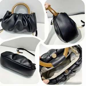 Detail of black pleated cloud bag featuring wooden round handle and magnetic closure