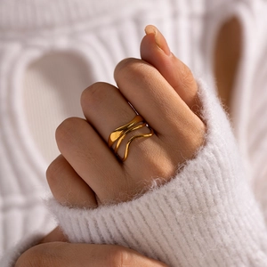 Macro detail of a triple-layered gold wavy irregular ring worn on a finger