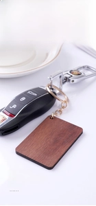 Macro shot of a wooden rectangular keychain attached to a car key on white background