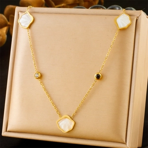 Detail of gold necklace featuring white floral shell charms and delicate crystal accents