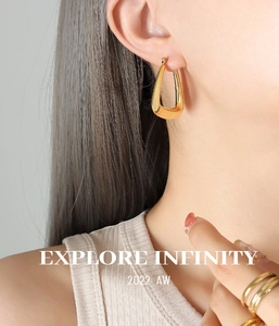 Detail shot of a model wearing a geometric U-shaped gold plated titanium steel earring