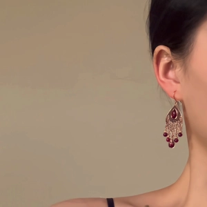 Boucles d'oreilles ethniques en bronze avec motifs évidés et perles rouge foncé sur modèle