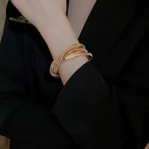 Gold multi-layer snake chain bracelet with sleek metal clasp on a model's wrist