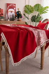 Macro detail of red Christmas tablecloth featuring white reindeer patterns and fringe edge