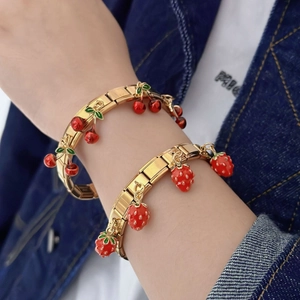 Fashionable golden stainless steel strawberry and cherry charm bracelets on a wrist